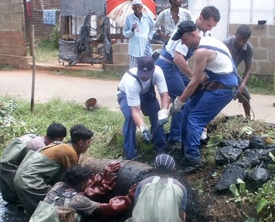 FWA Mitarbeiter und Einheimische ziehen Unrat aus dem Abwasserkanal in Sri Lanka